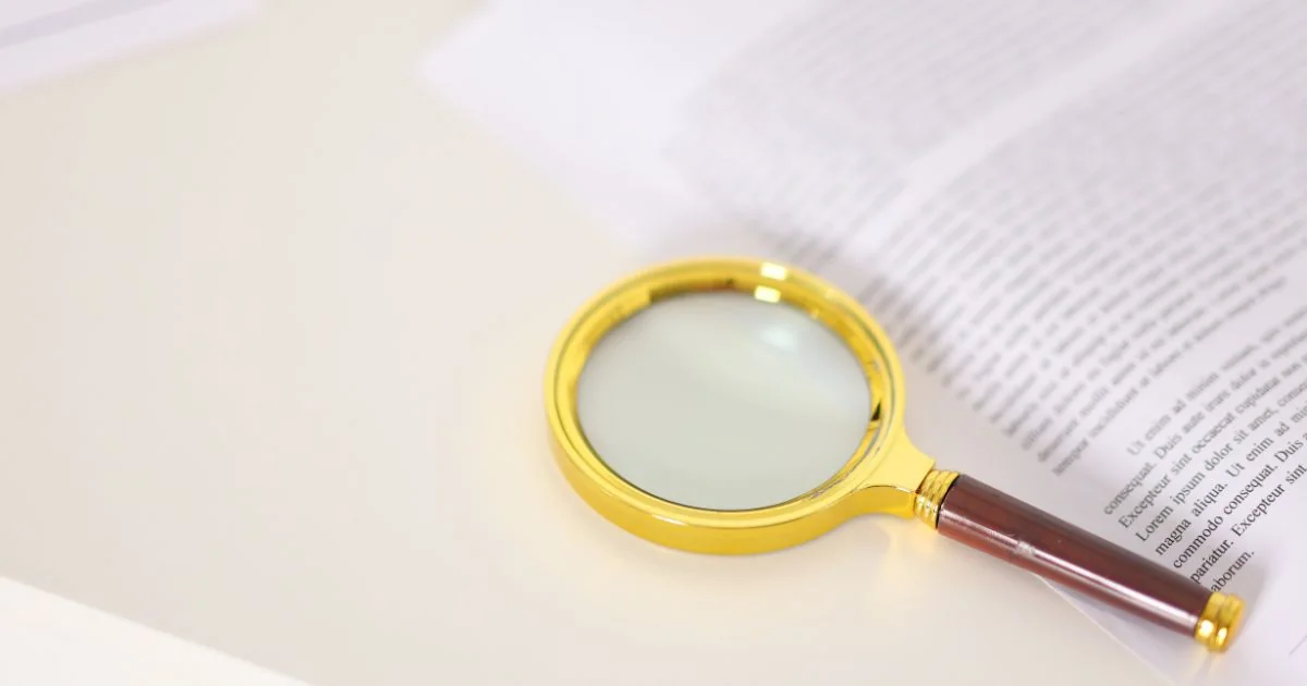 A golden-rimmed magnifying glass on an open book